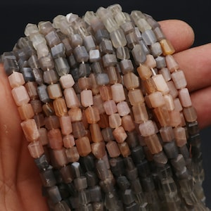 Könnte beinhalten: Eine Strähne facettierter Sunstone-Perlen in Grautönen, Braun und Orange. Die Perlen sind rechteckig und haben eine leicht unregelmäßige Form.