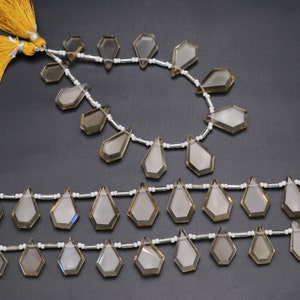 Puede incluir: Una hebra de cuentas de piedras preciosas de color marr&oacute;n claro con forma de l&aacute;grima facetada. Las cuentas est&aacute;n enhebradas en un cord&oacute;n blanco con separadores plateados. La hebra mide aproximadamente 45 cm de largo.