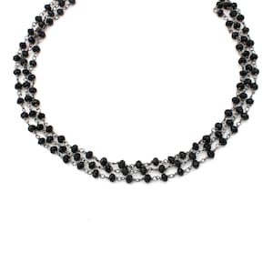 May include: A layered necklace with black beads and silver chain links.
