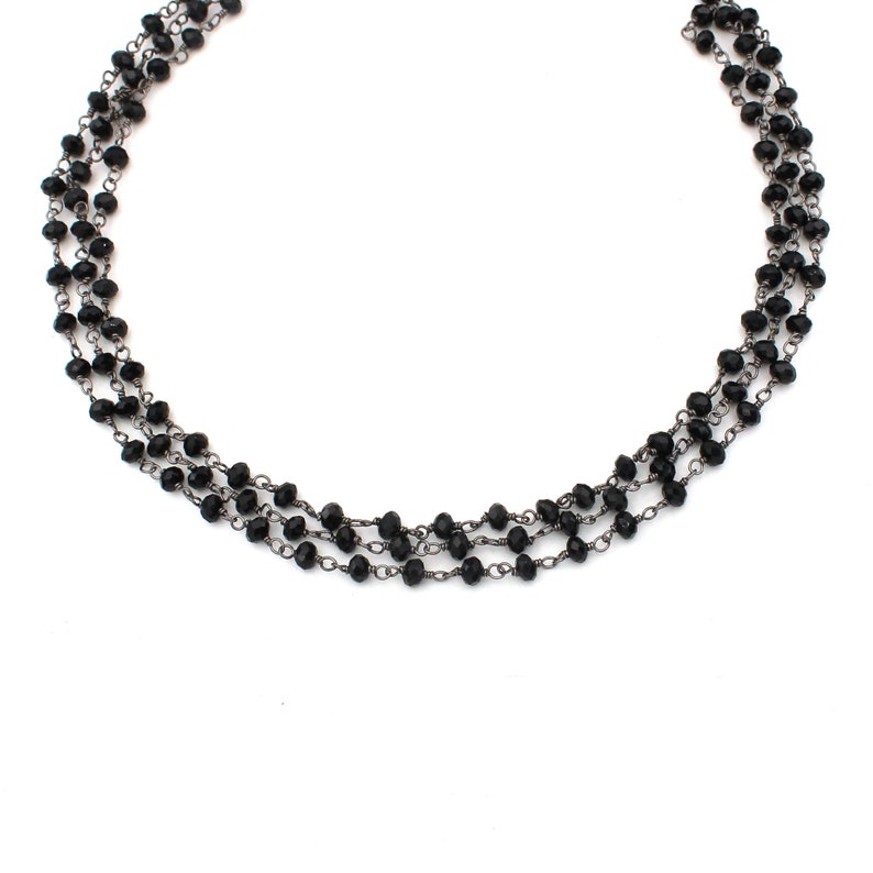 May include: A layered necklace with black beads and silver chain links.