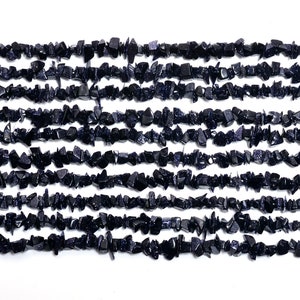 Può includere: Un filo di schegge di pietra preziosa di sabbia blu. Le schegge sono di forma irregolare e hanno un colore blu scuro con una finitura scintillante.