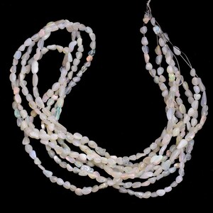 Peut inclure: Plusieurs brins de perles de pierres précieuses d'opale blanche. Les perles ont une forme ovale irrégulière et sont enfilées ensemble. Les opales sont blanc laiteux avec des reflets irisés. Le fond est noir uni.
