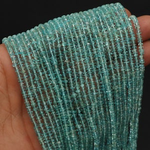 Peut inclure: Plusieurs brins de petites perles de pierres précieuses bleu clair. Les perles sont de taille et de forme uniformes, avec un aspect légèrement aplati en forme de disque. Les perles sont enfilées ensemble, créant un effet fluide et texturé.
