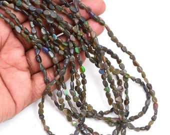May include: Strands of dark, oval-shaped opal beads in shades of gray, brown, and green. The beads have a polished, smooth texture and display flashes of color. The beads are strung together, ready for jewelry making or crafting.
