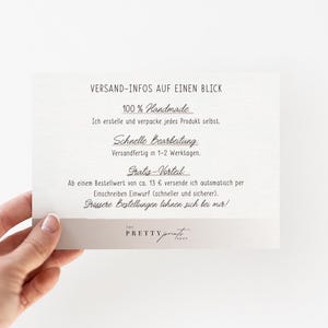 May include: A hand holding a cream-colored card with black text. The card reads "VERSAND-INFOS AUF EINEN BLICK" and details about handmade products, processing time, and shipping. The card has a light gray border and the logo "THE PRETTY PRINT" at the bottom.
