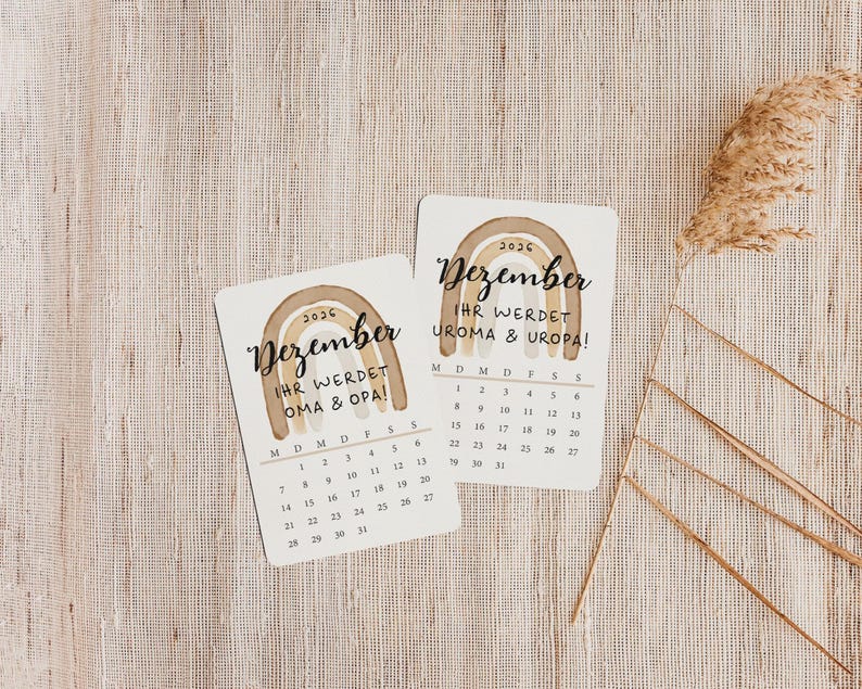 May include: Two small, rectangular cards with a watercolor rainbow design and the word "Dezember" in script. The cards display a calendar for December 2026, with the text "IHR WERDET OMA & OPA!" and "UROMA & UROPA!" in German.