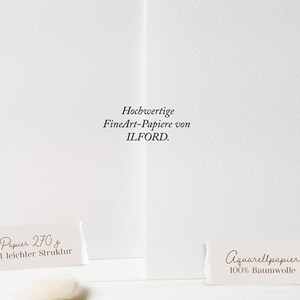 May include: Two sheets of white paper with different textures are displayed. Text on the image reads "Hochwertige FineArt-Papiere von ILFORD." A label reads "Papier 270 g mit leichter Struktur." Another label reads "Aquarellpapier 100% Baumwolle."