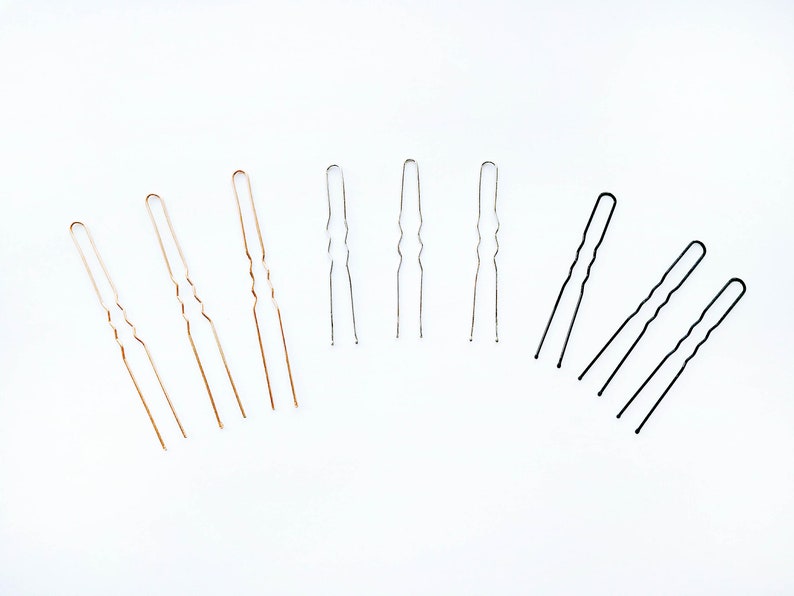 May include: A set of hair pins in three colors: gold, silver, and black. The pins are all the same size and shape, with a wavy design.
