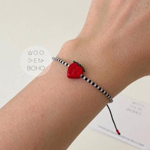 Pulseira Nancy com pingente de morango, contas pretas e brancas.