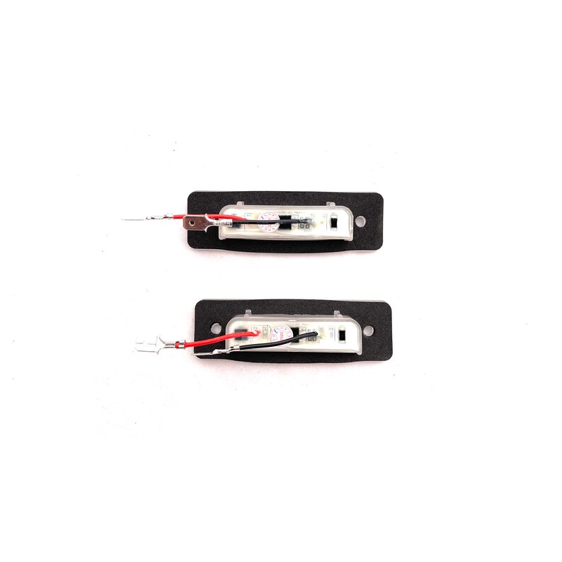 May include: Two black rectangular LED light fixtures with clear lenses and red and black wires attached. The lights are on a white background.