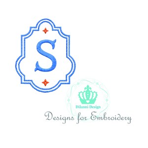 Puede incluir: Un monograma azul con la letra S en un marco azul y blanco con estrellas rojas. El marco tiene un borde festoneado. El texto "Dilanni Design" y "Designs for Embroidery" está debajo del monograma.