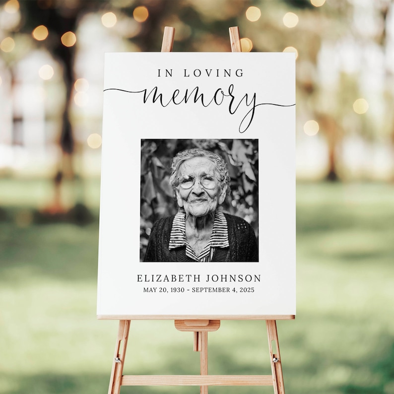 May include: A white sign with black text that reads "In loving memory" with a black and white photo of a woman and the text "Elizabeth Johnson May 20, 1930 - September 4, 2025".