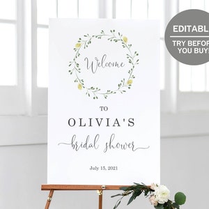Puede incluir: Un cartel de bienvenida blanco con una corona floral verde y amarilla, el texto "Bienvenido al baby shower de Olivia" y la fecha "15 de julio de 2021".