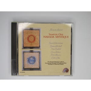 Könnte beinhalten: Ein CD-Gehäuse mit gelbem Hintergrund und einem Bild eines roten und blauen Kreises. Der Text auf dem Gehäuse lautet "Narada Artists Sampler One Narada Mystique" und listet die Künstler auf: David Arkenstone, Bruce Mitchell, Peter Buffett, Carel Nethen, Peter Maunu und Colin Chin. Der Text besagt auch: "The Narada Mystique Label is Exclusively Devoted To Exploring New Frontiers In Electronic Music."