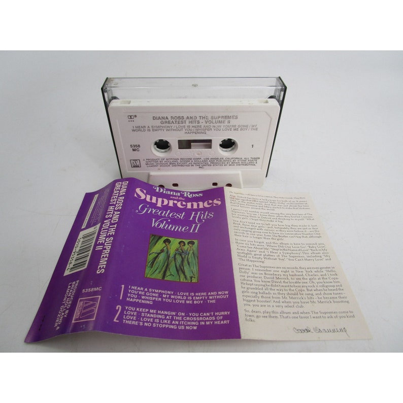 May include: A purple and white cassette tape case with a photo of Diana Ross and the Supremes on the front. The case has the title "Diana Ross and the Supremes Greatest Hits Volume II" printed on it. The back of the case has a description of the album and a list of the songs included.