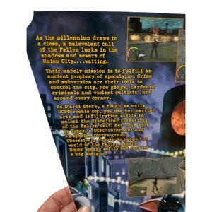 Pu&ograve; includere: Un primo piano della copertina di una scatola di videogiochi con uno sfondo blu scuro e testo giallo. Il testo recita "Mentre il millennio volge al termine, un culto malvagio dei Caduti si nasconde nelle ombre e nelle fogne di Union City...in attesa." L'immagine presenta anche uno screenshot del gioco, che mostra un personaggio in un vicolo buio.