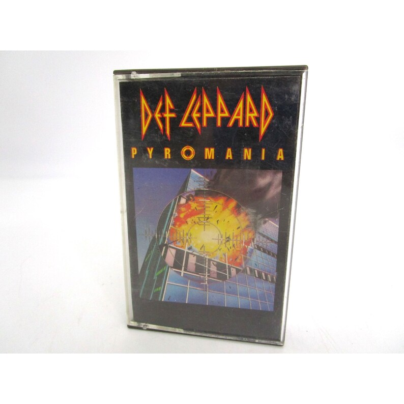 May include: A black cassette tape with a picture of a building exploding. The text "Def Leppard" and "Pyromania" are printed on the front of the tape.
