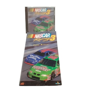 Può includere: Un manuale di gioco NASCAR Racing 3 verde e nero con un'auto da corsa verde sulla copertina. L'auto ha le parole "Interstate Batteries" e "MBNA" sul lato. Il manuale è accanto a una custodia per CD con lo stesso titolo di gioco.