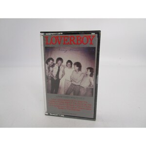 May include: A black cassette tape case with a red and white "LOVERBOY" title. The case features a photo of five men in a band, with the text "LOVIN' EVERY MINUTE OF IT" and a list of song titles.