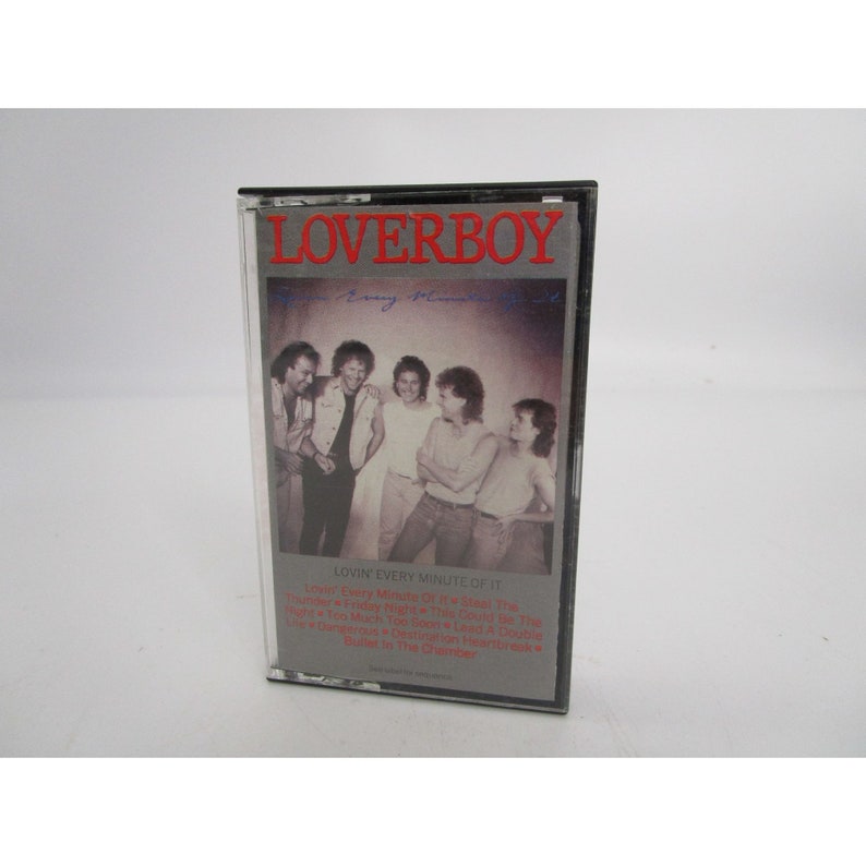 May include: A black cassette tape case with a red and white "LOVERBOY" title. The case features a photo of five men in a band, with the text "LOVIN' EVERY MINUTE OF IT" and a list of song titles.