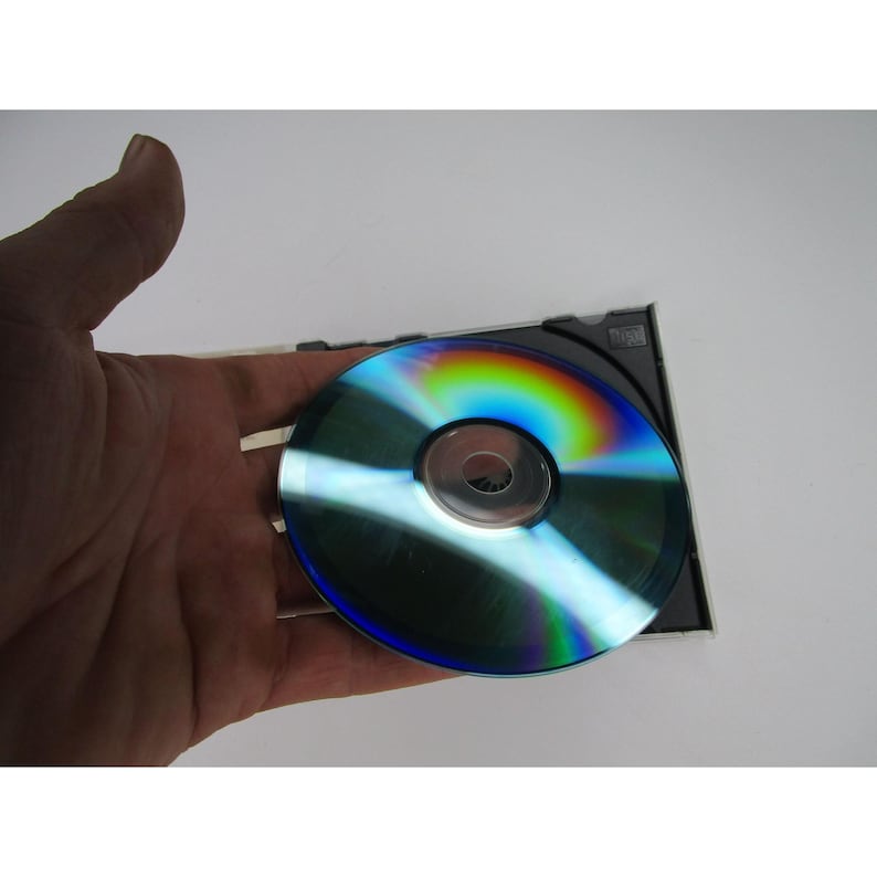 May include: A silver compact disc with a rainbow iridescent sheen. The disc is in a black jewel case.
