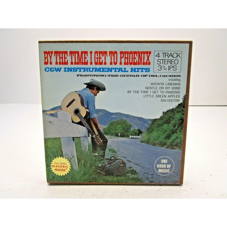 K&ouml;nnte beinhalten: Ein Vintage-Schallplattencover mit einem Cowboy, der auf einer Landstra&szlig;e Gitarre spielt. Der Albumtitel lautet "By The Time I Get To Phoenix" und enth&auml;lt C&W Instrumental Hits von Del Cacher. Das Albumcover ist braun mit einem wei&szlig;en Rand und zeigt ein Foto eines Cowboys in einem braunen Hut und einem blauen Hemd, der Gitarre spielt.