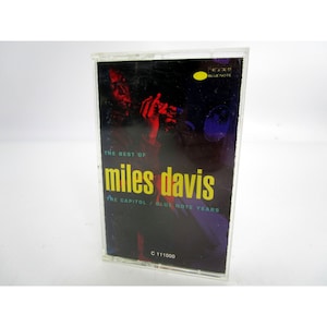 Op de afbeelding: Een cassettebandje met een zwart-rode afbeelding van Miles Davis die trompet speelt. De tekst op de cassetteband staat "The Best of Miles Davis The Capitol/Blue Note Years" en "C 111000".