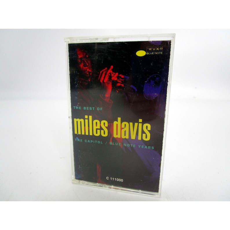 Op de afbeelding: Een cassettebandje met een zwart-rode afbeelding van Miles Davis die trompet speelt. De tekst op de cassetteband staat "The Best of Miles Davis The Capitol/Blue Note Years" en "C 111000".