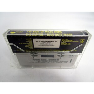 Op de afbeelding: Een zwarte cassettebanddoos met een transparante plastic hoes. De doos heeft een wit label met de tekst "The Best of Miles Davis The Capitol/Blue Note Years". Het label bevat ook de tekst "Side One" en "Side Two" met een lijst van nummers op elke kant.