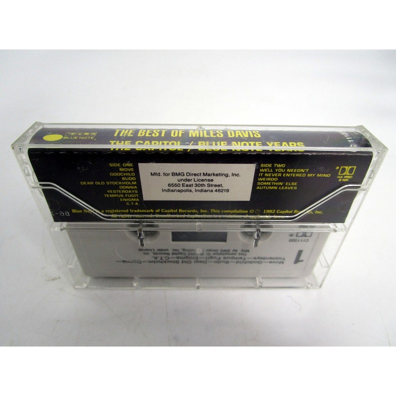 Op de afbeelding: Een zwarte cassettebanddoos met een transparante plastic hoes. De doos heeft een wit label met de tekst "The Best of Miles Davis The Capitol/Blue Note Years". Het label bevat ook de tekst "Side One" en "Side Two" met een lijst van nummers op elke kant.