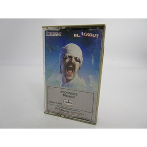 May include: A cassette tape case with a black and white photo of a man with a white bandage over his eyes. The text on the case reads "SCORPIONS Blackout MCR-4-1-4039 mercury Manufactured and Marketed by PolyGram Records&trade;".