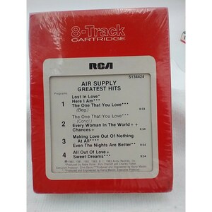 May include: A red 8-track cartridge case with a white label. The label features the RCA logo, the title "Air Supply Greatest Hits", and a list of songs with their corresponding track numbers and run times. The case is labeled with the product number S134424.