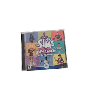 Puede incluir: Caja de CD del juego The Sims Livin' Large Expansion Pack. La caja es negra con una ventana de plástico transparente que muestra la portada del juego. La portada presenta un collage colorido de personajes de los Sims y el título del juego. El juego está clasificado como T para adolescentes por la PEGI.