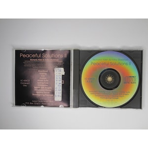 Pu&ograve; includere: Una custodia per CD con sfondo nero e un'etichetta bianca. L'etichetta riporta il titolo "Peaceful Solutions II" e i nomi "Richard Allen & Kirby Shelstad". La custodia per CD include anche un elenco di canzoni e i loro tempi.