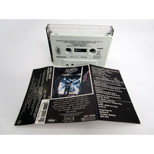 May include: A black cassette tape with a white label. The label has the text "April Wine Power Play" and a picture of a man playing a guitar. The text "Anything you want, you got it... Enough is enough if you see Kay... What if we fall in love... Waiting on a miracle... Doin' it right... Ain't got your love... Blood money... Tell me why... Runners in the night." is printed on the label.