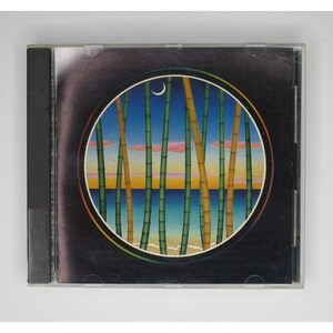 May include: A CD cover with a circular image of a beach scene with a crescent moon in the sky. The scene is framed by tall green and yellow bamboo stalks.