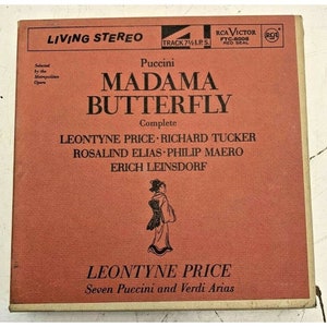 Puede incluir: Una portada de álbum de disco rojo y blanco con el título "MADAMA BUTTERFLY" de Puccini. El álbum presenta una ilustración en blanco y negro de una mujer con un kimono japonés tradicional. El álbum es una grabación completa de la ópera y presenta a Leontyne Price, Richard Tucker, Rosalind Elias, Philip Maero y Erich Leinsdorf.