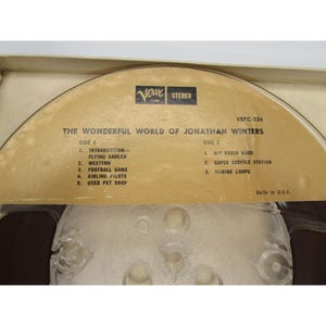 May include: A vintage reel-to-reel audio tape with a brown label. The label reads "The Wonderful World of Jonathan Winters" and lists the songs on each side of the tape. The tape is labeled "Verve Tape Stereo" and "VSTC-234".