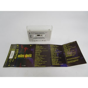 Op de afbeelding: Een cassettebanddoos met een witte achtergrond en zwarte tekst. De doos is open en toont de cassetteband erin. De band is gelabeld met "The Best of Miles Davis: The Capitol/Blue Note Years".
