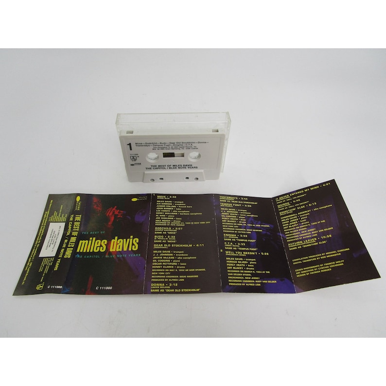 Op de afbeelding: Een cassettebanddoos met een witte achtergrond en zwarte tekst. De doos is open en toont de cassetteband erin. De band is gelabeld met "The Best of Miles Davis: The Capitol/Blue Note Years".