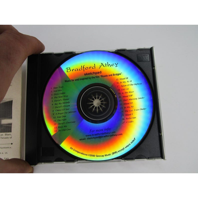 May include: A silver compact disc with a rainbow-colored design. The disc is labeled "Bradford Athey sketchpad" and features a list of song titles, including "Daryl's Dream", "A Place For", and "Mood VI".