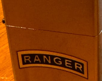 May include: A silver lighter with a brown metal casing and the word "RANGER" printed in black on a gold patch.