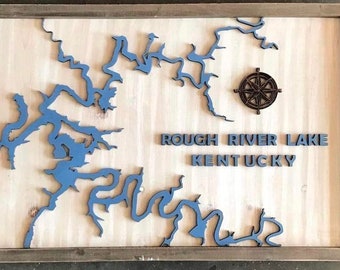 May include: A wooden wall art piece featuring a blue silhouette of Rough River Lake, Kentucky. The piece includes a compass and the text "ROUGH RIVER LAKE KENTUCKY".