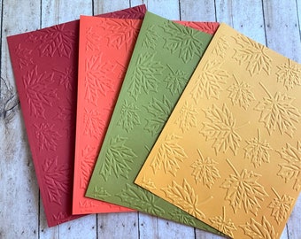 May include: Four sheets of cardstock with an embossed maple leaf pattern. The sheets are red, orange, green, and yellow.