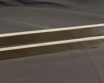May include: A silver metal towel bar with a rectangular shape and a single, horizontal, rectangular cutout.