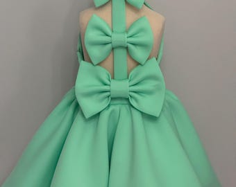 May include: A mint green dress with three large bows on the back. The dress has a full skirt and is made of a soft, flowing fabric.