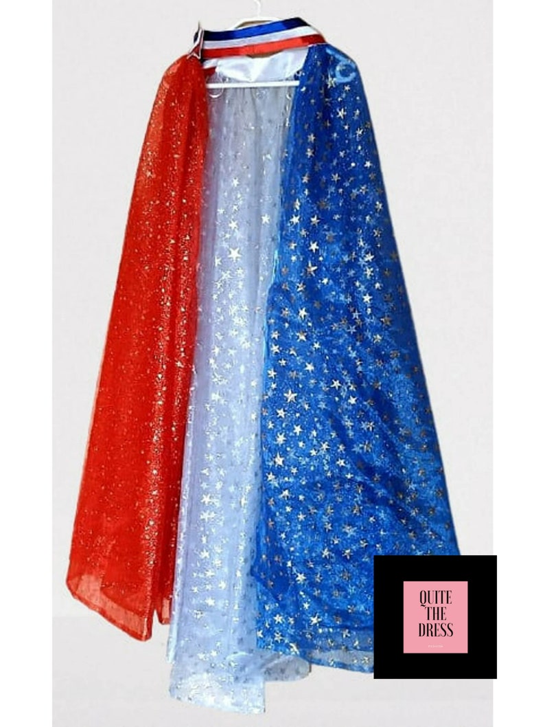 May include: A red, white, and blue cape with gold stars. The cape is made of sheer fabric and has a white satin lining. The cape is trimmed with a red, white, and blue ribbon.