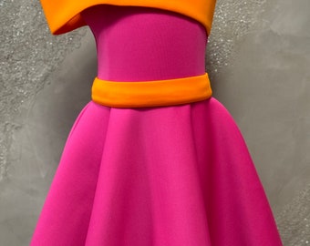 Puede incluir: Un vestido rosa con una tira asimétrica naranja brillante y un cinturón naranja a juego. El vestido tiene una falda acampanada y un corpiño sin mangas.