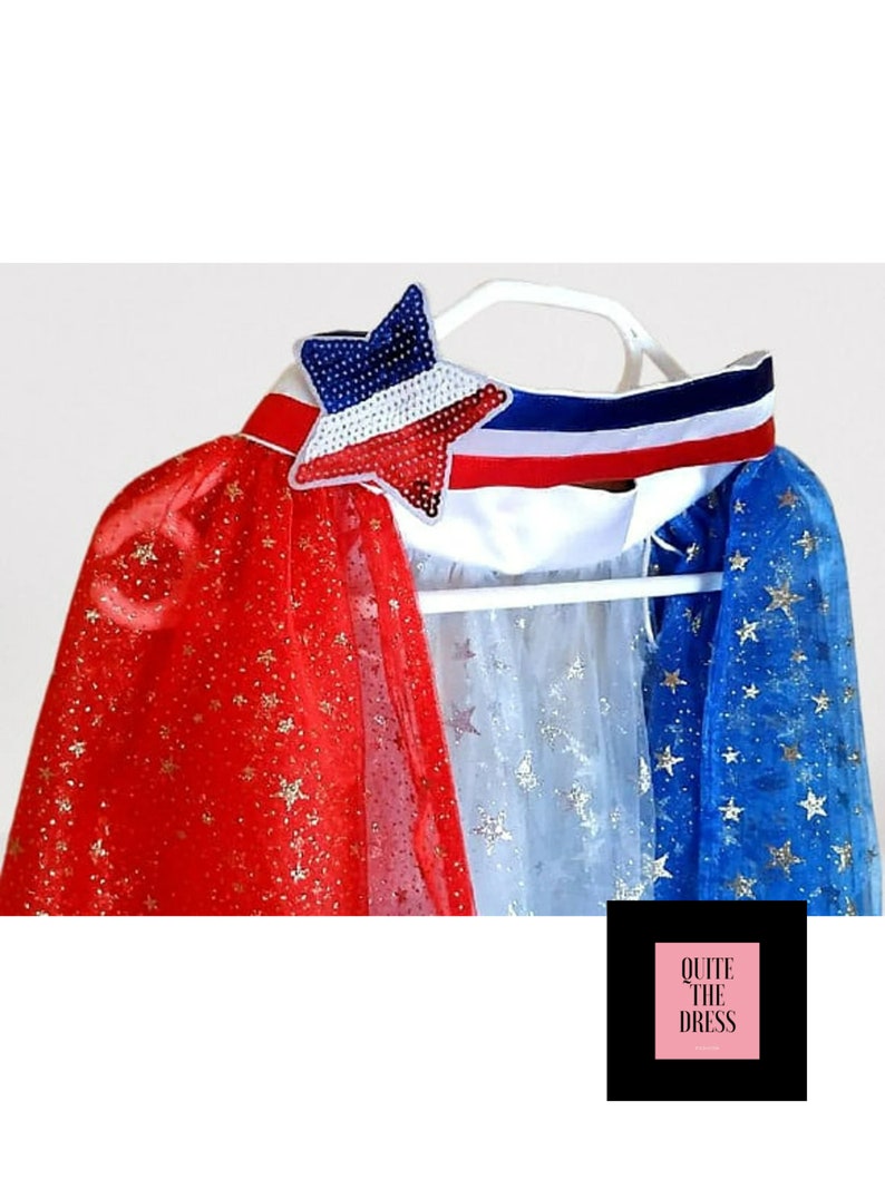 May include: Red, white, and blue cape with gold glitter stars. The cape has a white collar with a red, white, and blue ribbon and a sequined star.