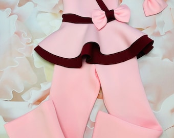 Puede incluir: Un conjunto de niña rosa y burdeos con una parte superior con volantes, un lazo y pantalones a juego.
